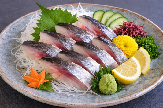 Sashimi platter with fish slices, cucumbers, lemon, and garnishes on a decorative plate.