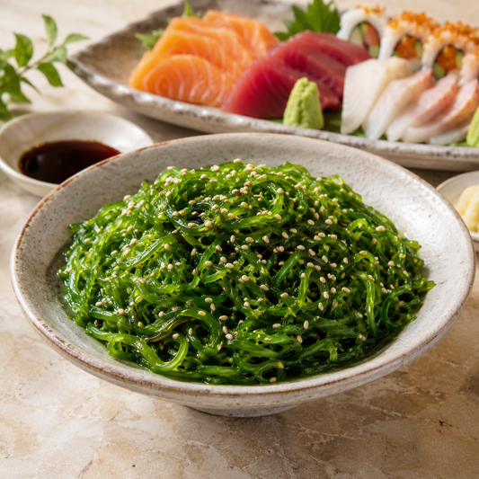 Chilled wakame seaweed salad with sesame served alongside sushi and sashimi
