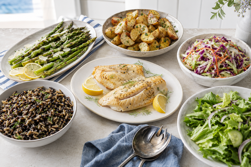 Seafood side dishes including asparagus, roasted potatoes, slaw, rice, and salad