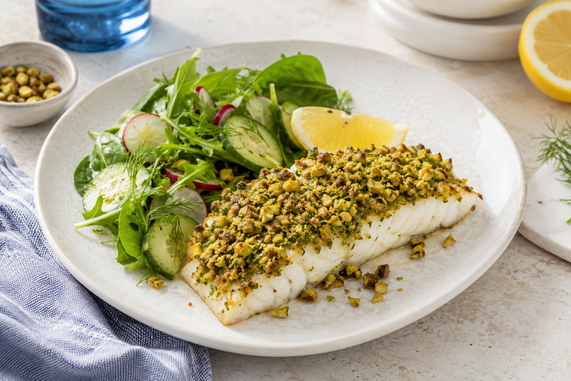 Pistachio-crusted white fish fillet with lemon and fresh greens