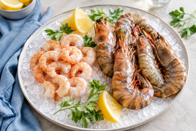 Shrimp and large prawns displayed side by side on ice for comparison