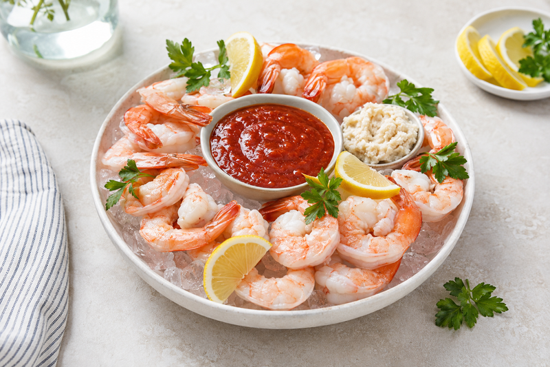 Chilled shrimp cocktail surrounding a bowl of classic red cocktail sauce