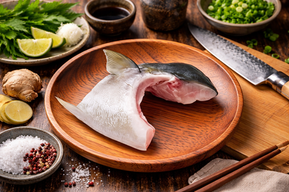 Raw fish on a wooden plate with ingredients and utensils on a wooden table