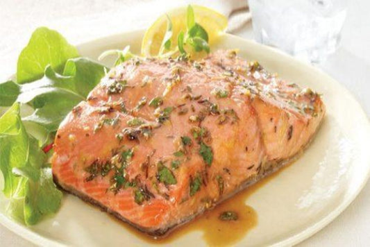 Grilled salmon with herbs on a white plate with salad